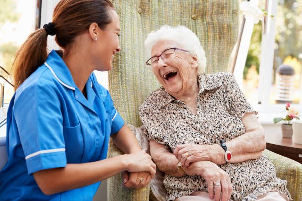 Caregiver smiling with an older adult at home